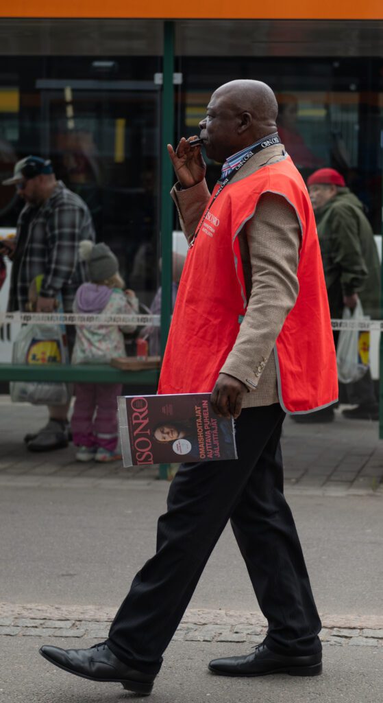 Valokuva, Iso numero -lehden myyjä punaisessa huomioliivissä.