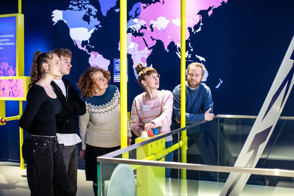Museo-opas ja ihmisiä seuraamassa opastusta.
